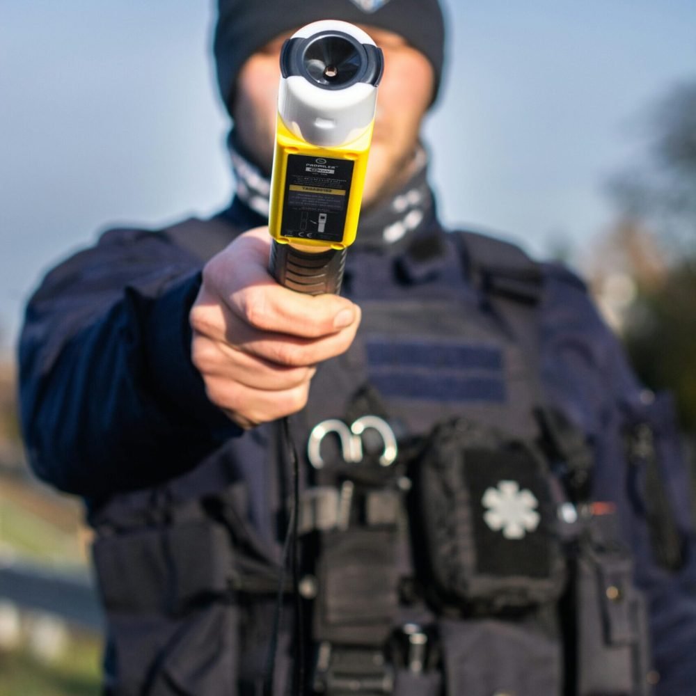 Police officer in uniform holds a breathalyzer for road safety checks.